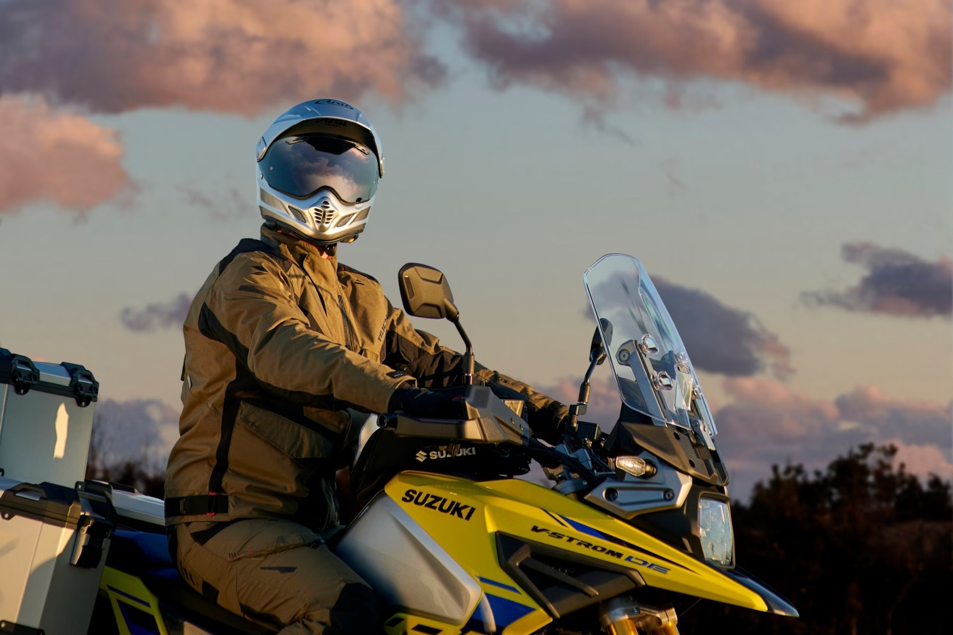 Motociclista en Suzuki V-Strom 1050DE amarilla al atardecer
