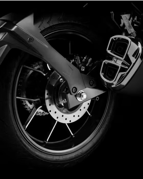 Primer plano del freno de disco trasero, llanta de aleación y salida de escape de la motocicleta Suzuki Gixxer