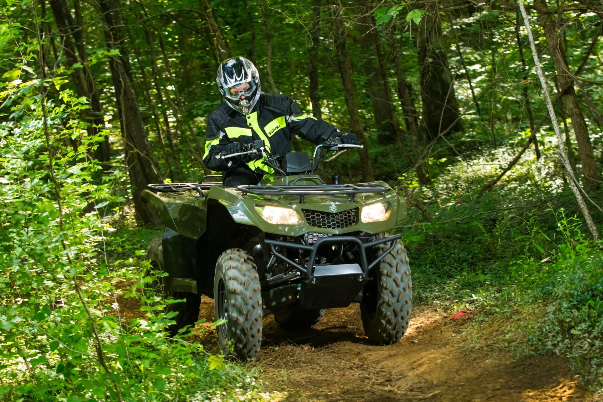 Conductor en Suzuki KingQuad 400 verde recorriendo un sendero off-road en el bosque