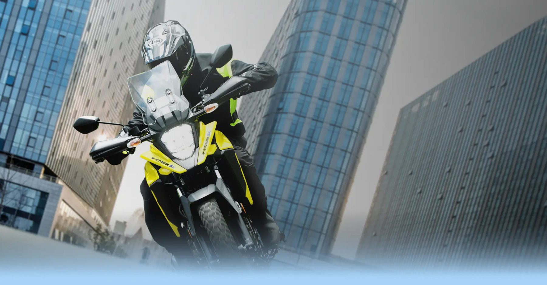 Piloto conduciendo una Suzuki V-Strom 250 amarilla en entorno urbano