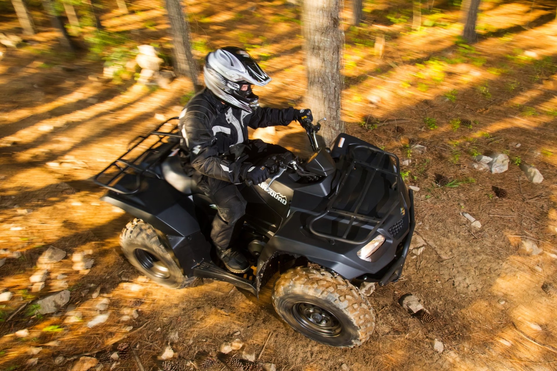 Conductor en Suzuki KingQuad 400 negro recorriendo un sendero off-road en el bosque