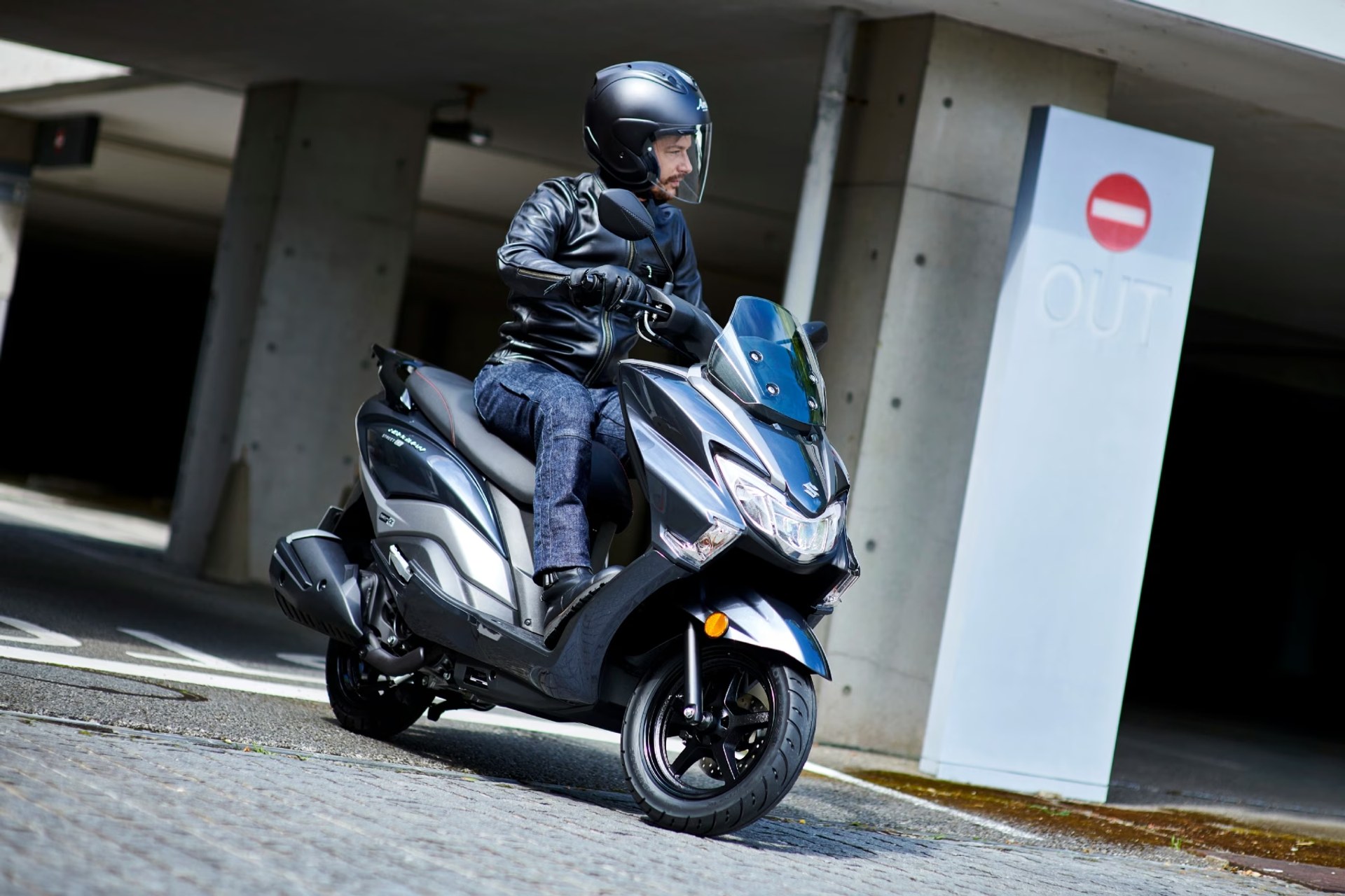 Piloto saliendo de un garaje en un scooter Suzuki Burgman Street 125EX gris