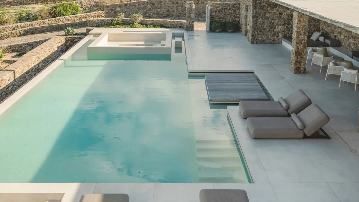 Luxury Mykonos villa with a private infinity pool, sun loungers and natural stone architecture.