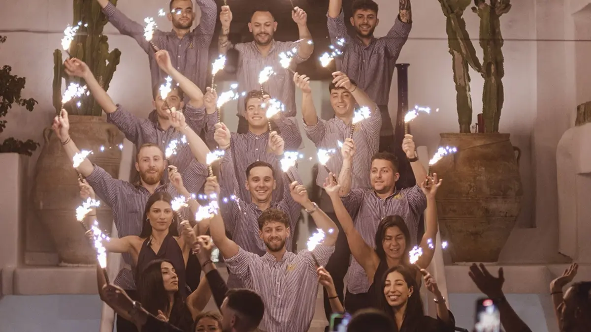 Mykonos hospitality team holding sparklers during a lively evening celebration at a luxury venue.