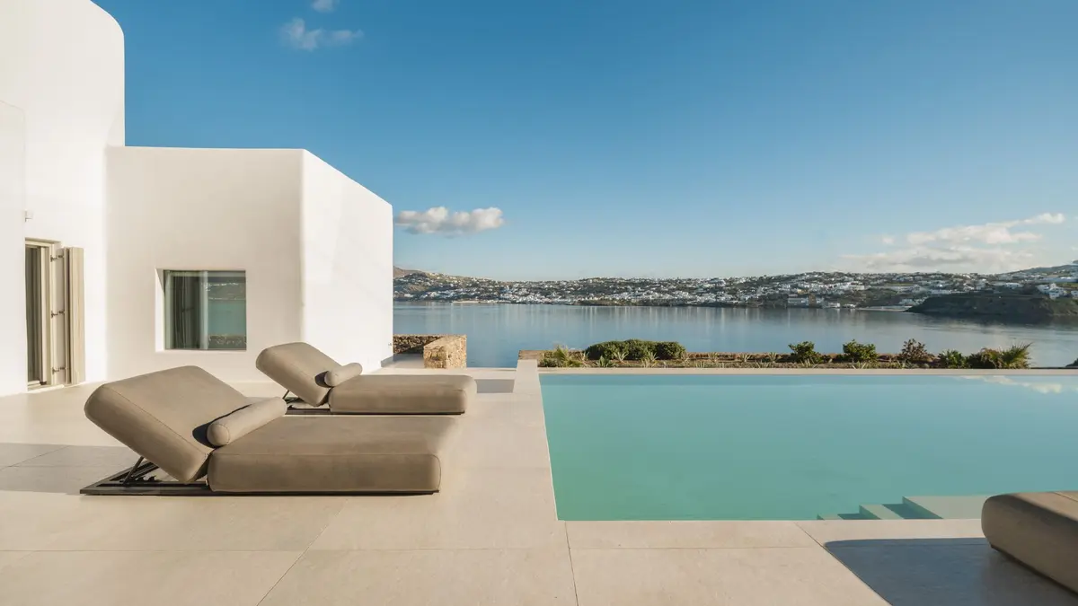 Luxury white villa in Mykonos with sun loungers, an infinity pool and panoramic views across the Aegean Sea.