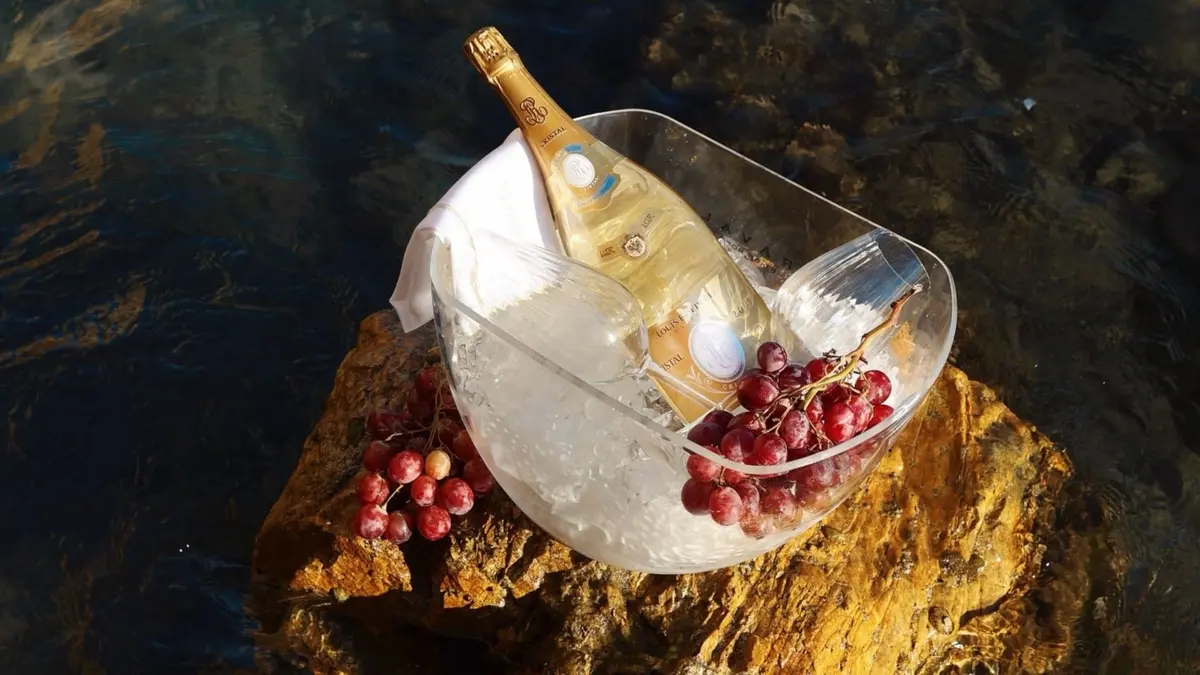 Chilled champagne with red grapes arranged on a seaside rock in Mykonos.