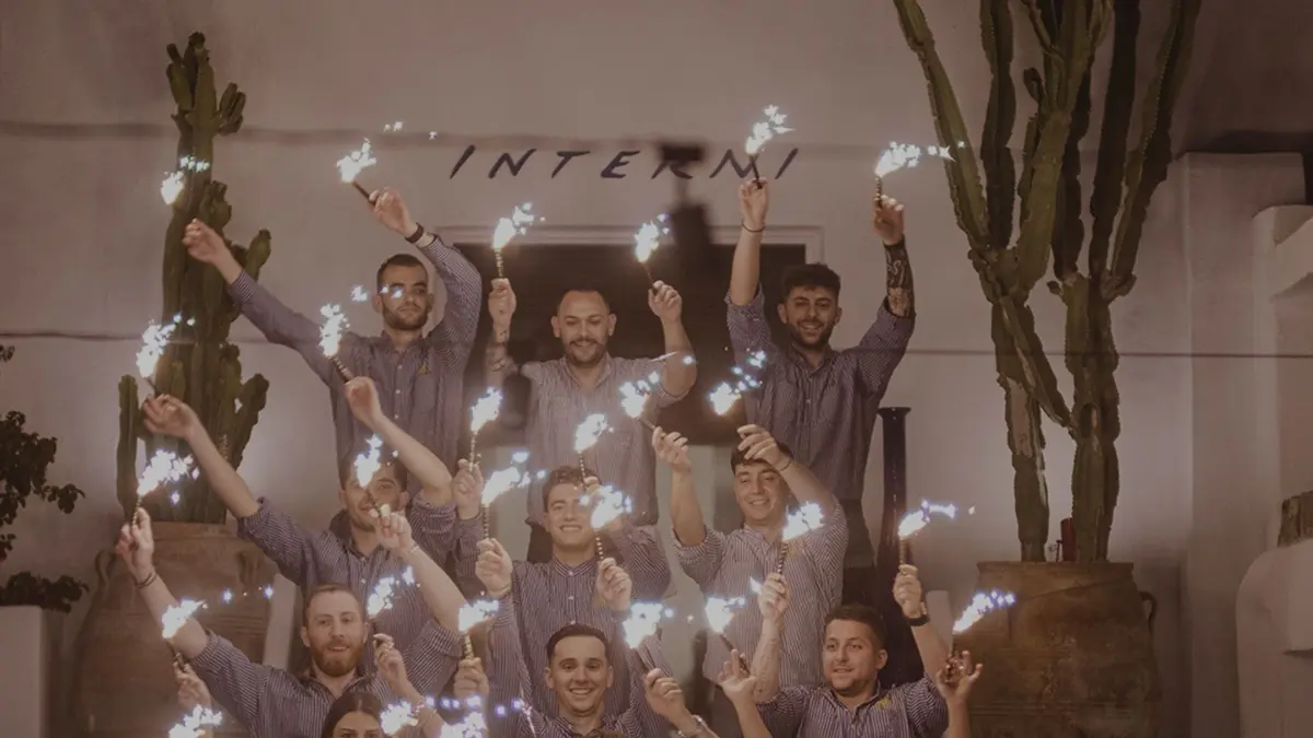 Mykonos restaurant staff holding sparklers during a lively evening celebration.