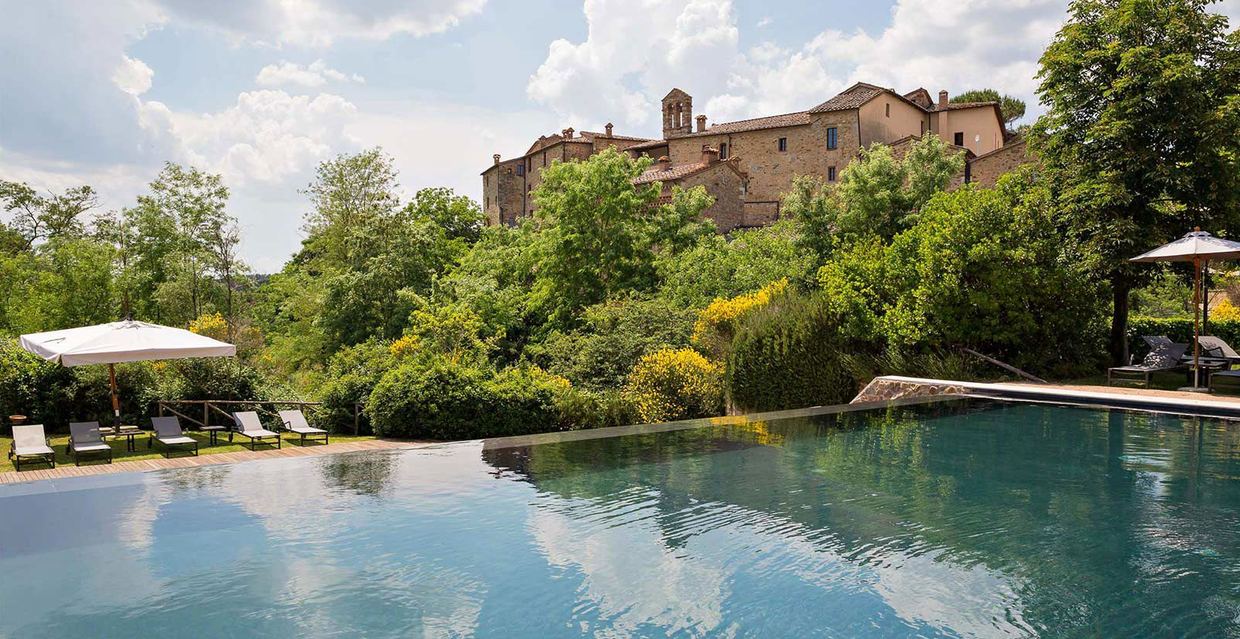 The infinity pool at Castel Monastero, with the medieval hamlet and its bell tower rising above the gardens
