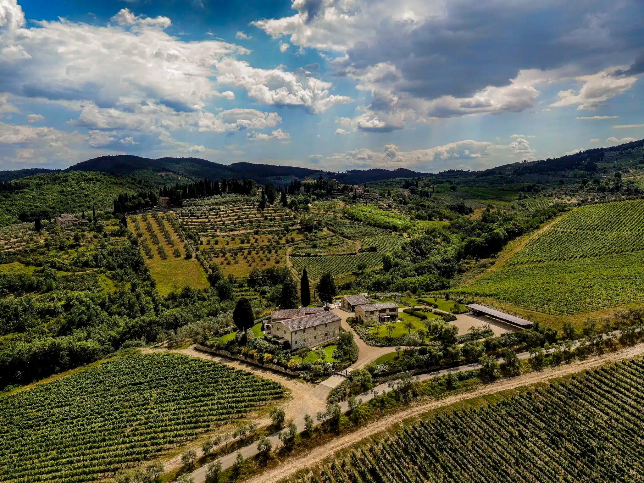 Aerial view of the Cabreo estate near Greve: stone farmhouses and gardens among vineyards, olive terraces and cypresses