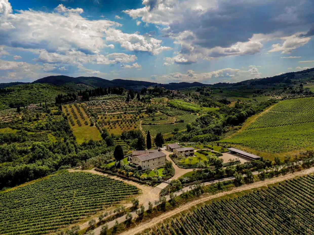 Aerial view of the Cabreo estate near Greve: stone farmhouses and gardens among vineyards, olive terraces and cypresses