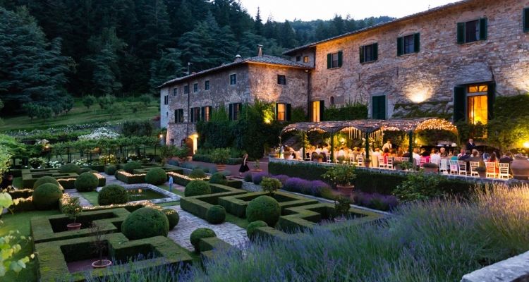 The walled garden of Badia a Coltibuono abbey restaurant, tables set beneath ancient stone arches