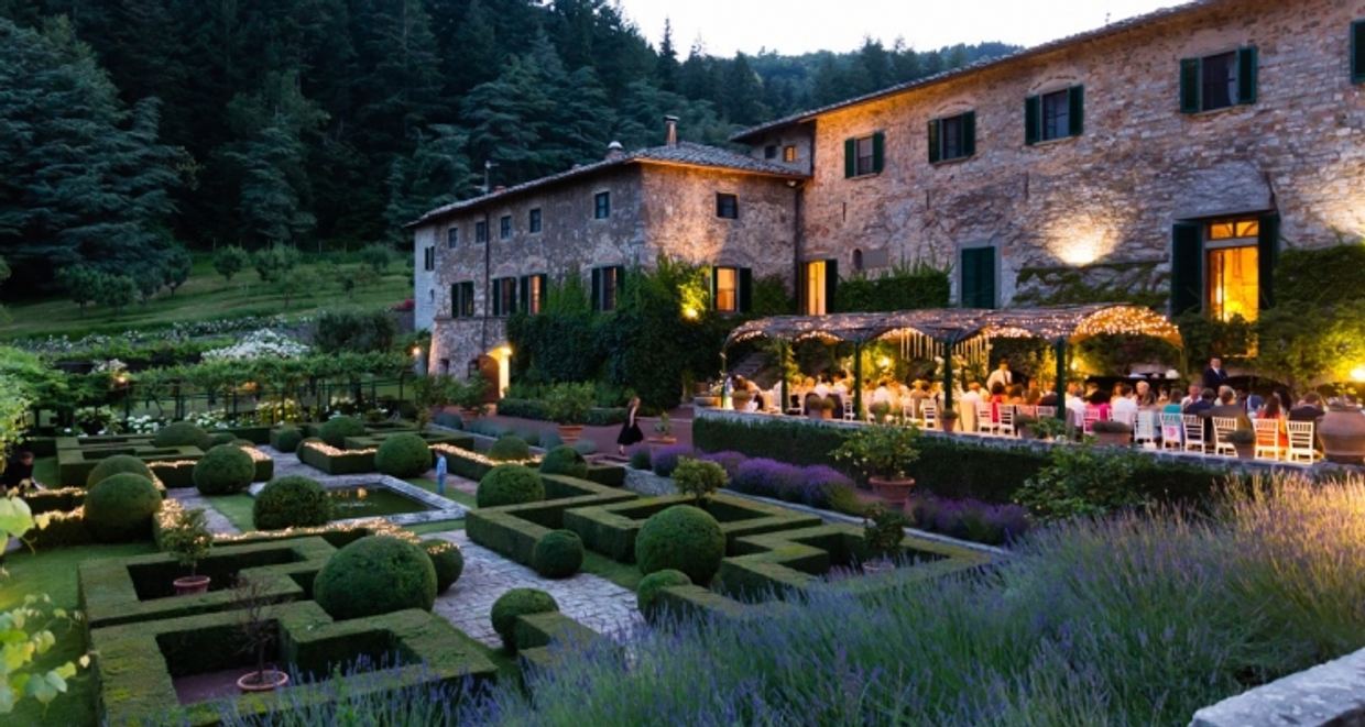 The walled garden of Badia a Coltibuono abbey restaurant, tables set beneath ancient stone arches