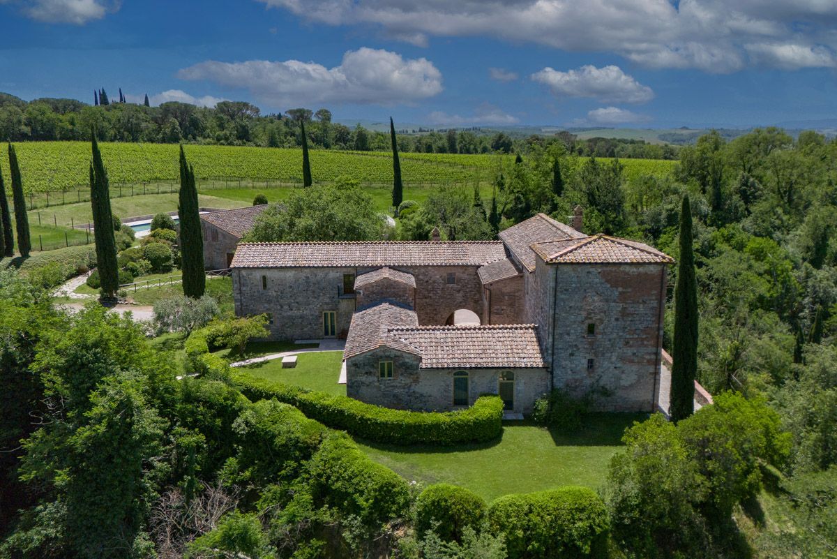 La Gazzara at Castell’in Villa: a stone farmhouse with lawns and cypresses, a swimming pool and vineyards behind