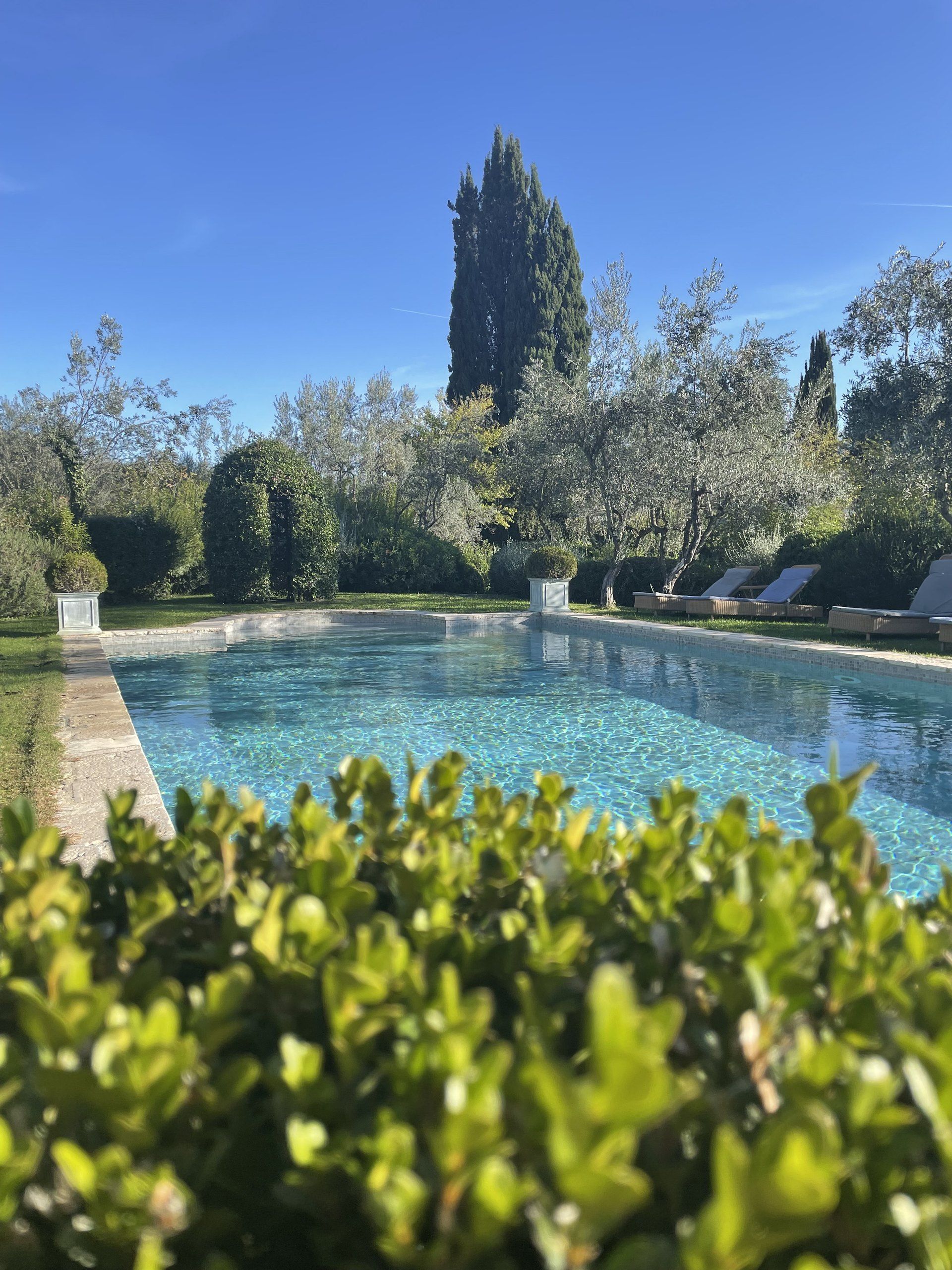 A stone-walled Tuscan villa with a cypress-lined pool