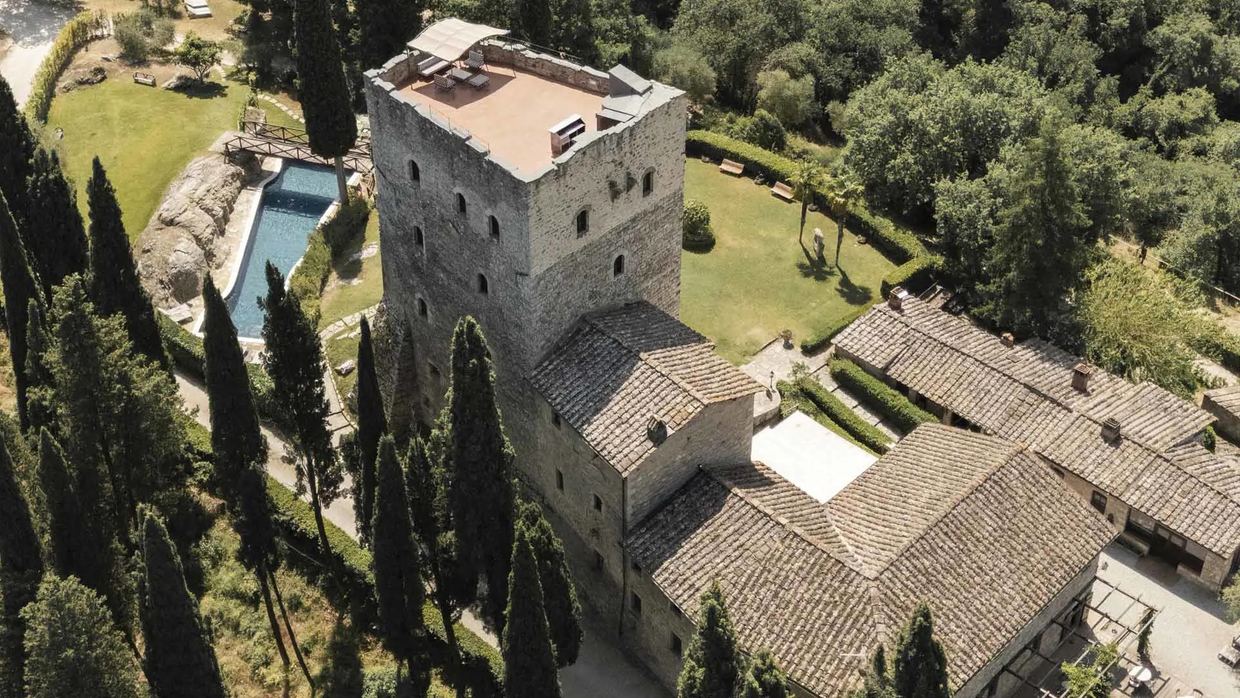The medieval tower of Castello di Tornano rising above Chianti Classico vineyards near Gaiole