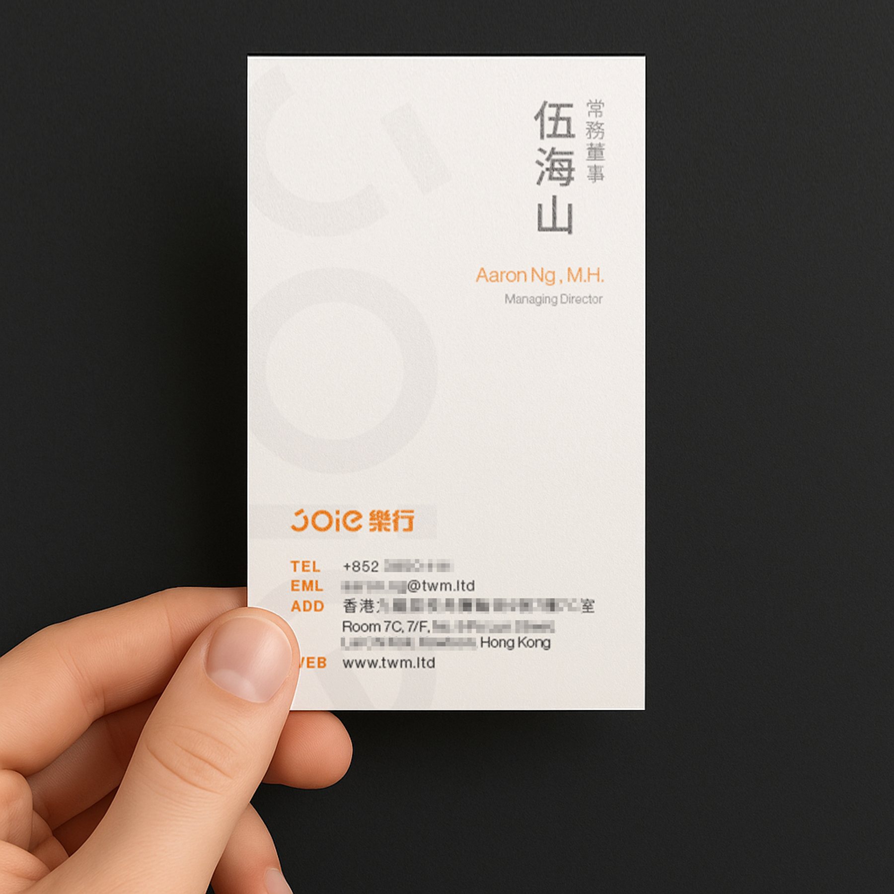 手持 JOIE 樂行白色名片，淺灰圓形視覺與橘色文字點綴。 / Hand holding JOIE Taxi white business card with light grey patterns and orange accents.