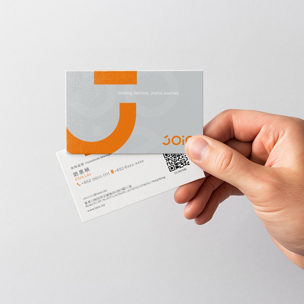 手持 JOIE 樂行灰橘名片,展示正反面設計。 / Hand holding JOIE Taxi grey-orange business card, showing both sides.
