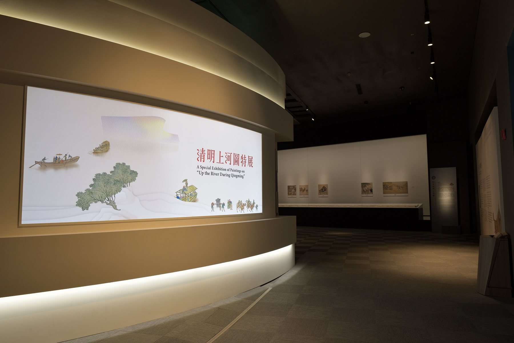 展場入口全景，弧形牆面與主視覺標題牆。/ Wide view of the entrance with the curved wall and title graphic.