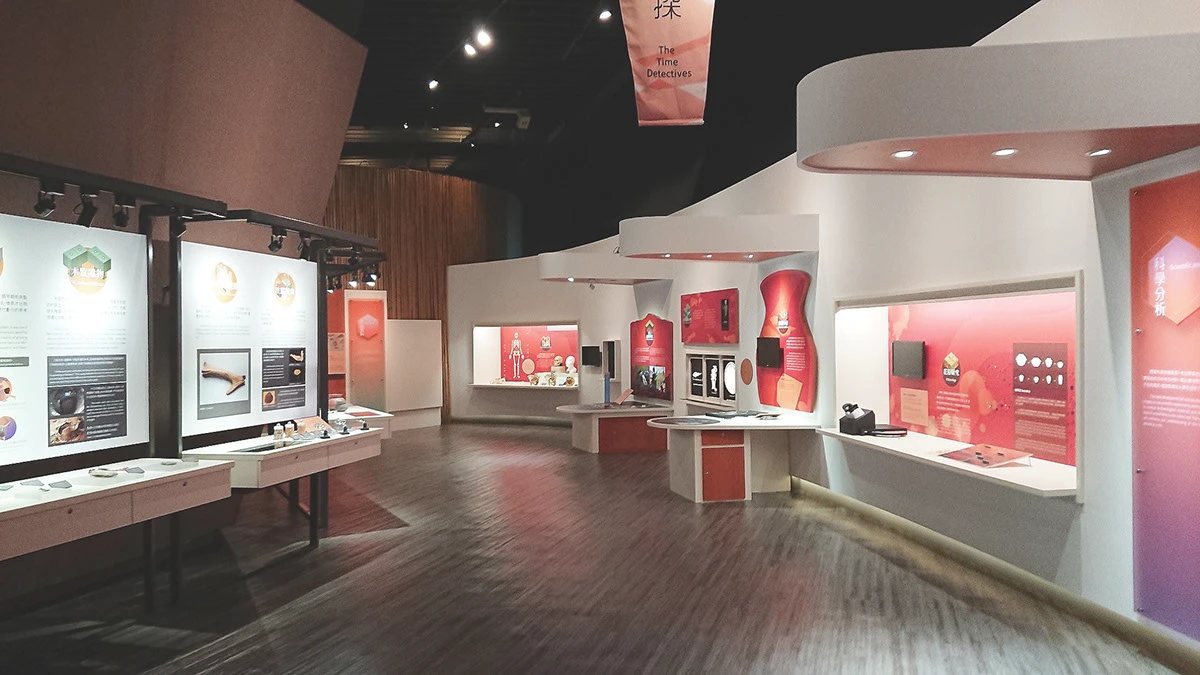 十三行博物館常設展考古工作站的展場實景,展示橘紅色圖文展板與互動桌面