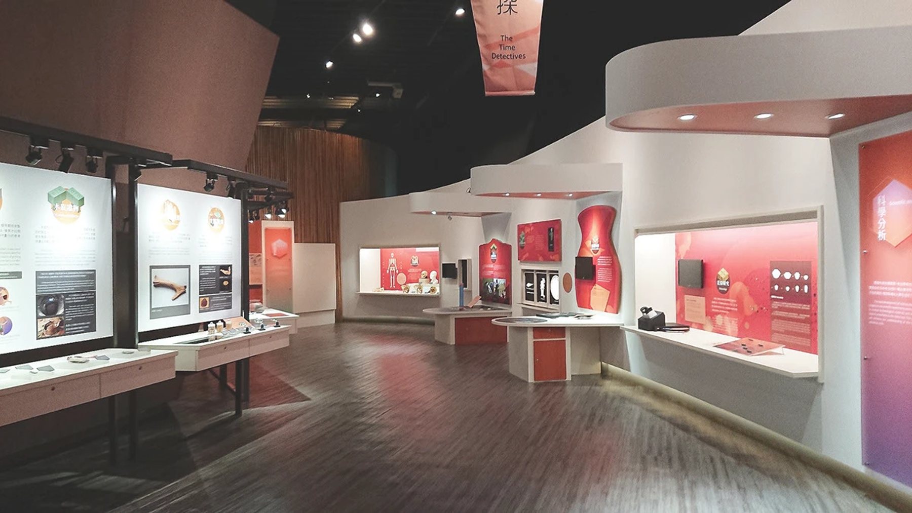 十三行博物館常設展考古工作站的展場實景，展示橘紅色圖文展板與互動桌面
