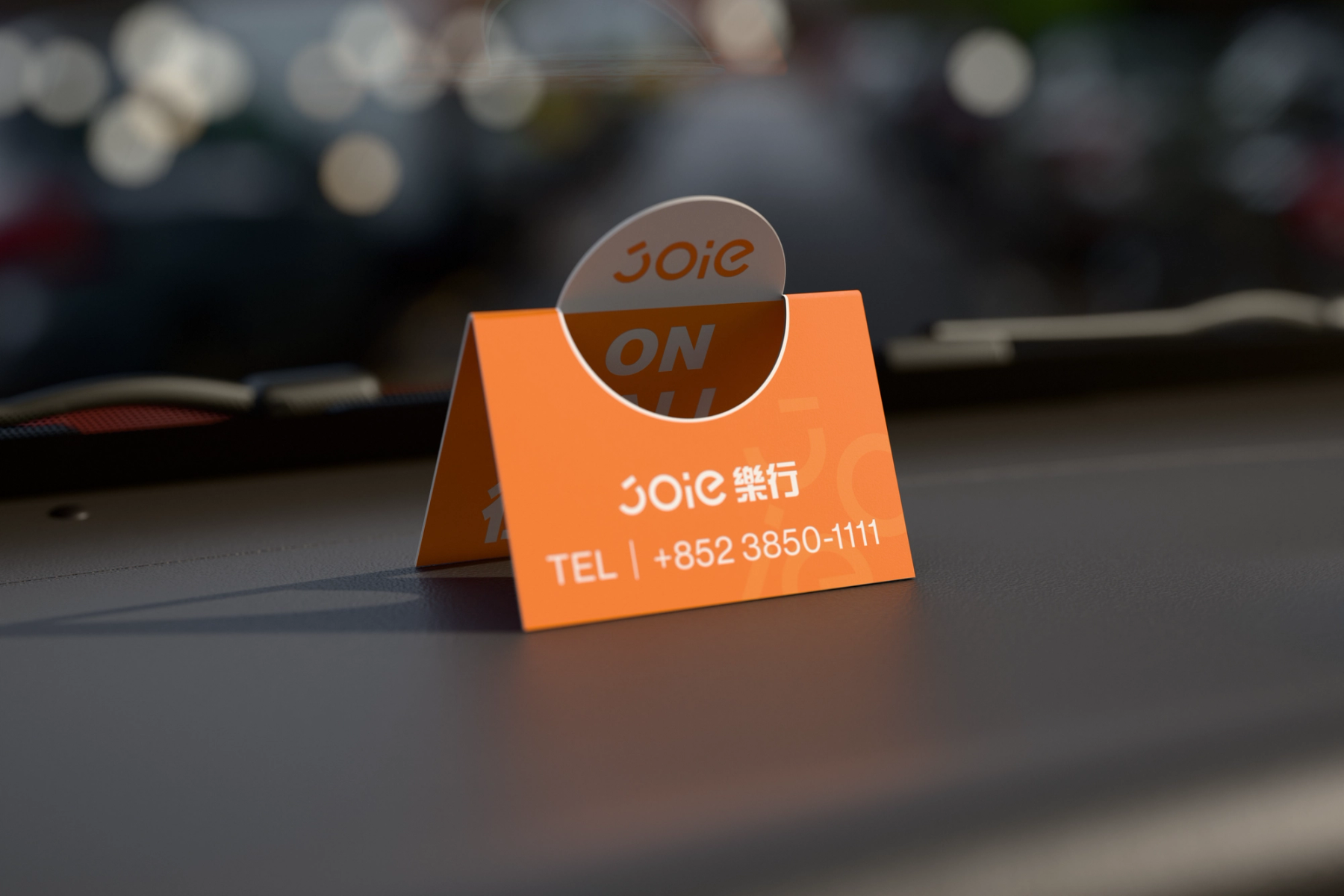 JOIE 樂行立牌放在儀表板上的日間車內 3D 情境，面向乘客顯示品牌與電話資訊