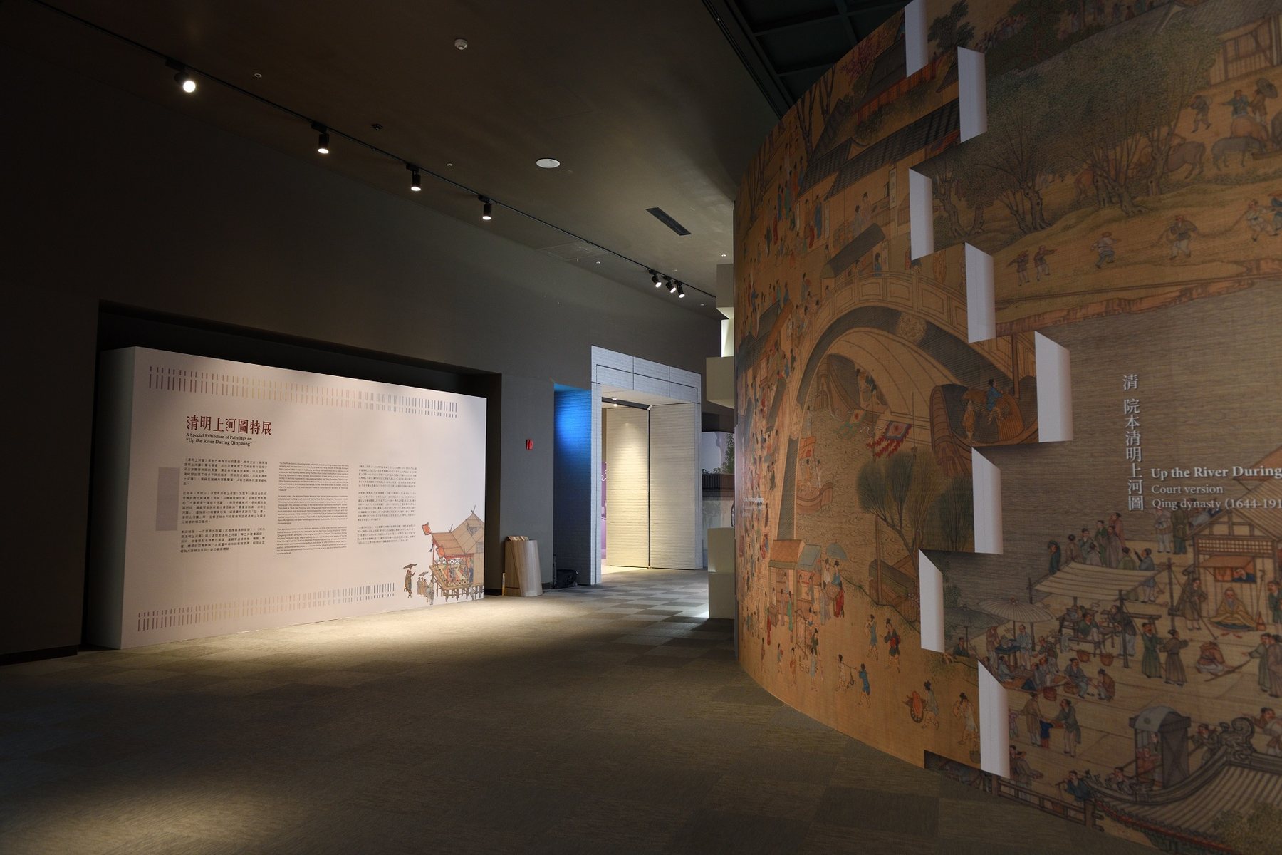 展場內放大輸出的清明上河圖弧形長牆與說明牆。/ An enlarged reproduction of the scroll on a curved wall beside the introduction panel.