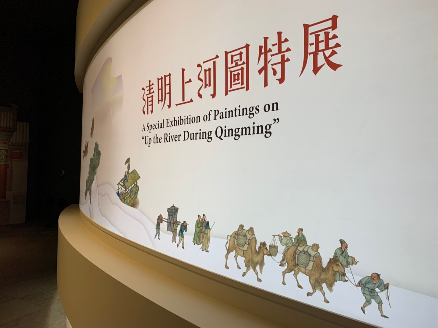 故宮南院弧形入口牆面,畫中人物與駱駝隊剪影沿牆展開成入場隊伍