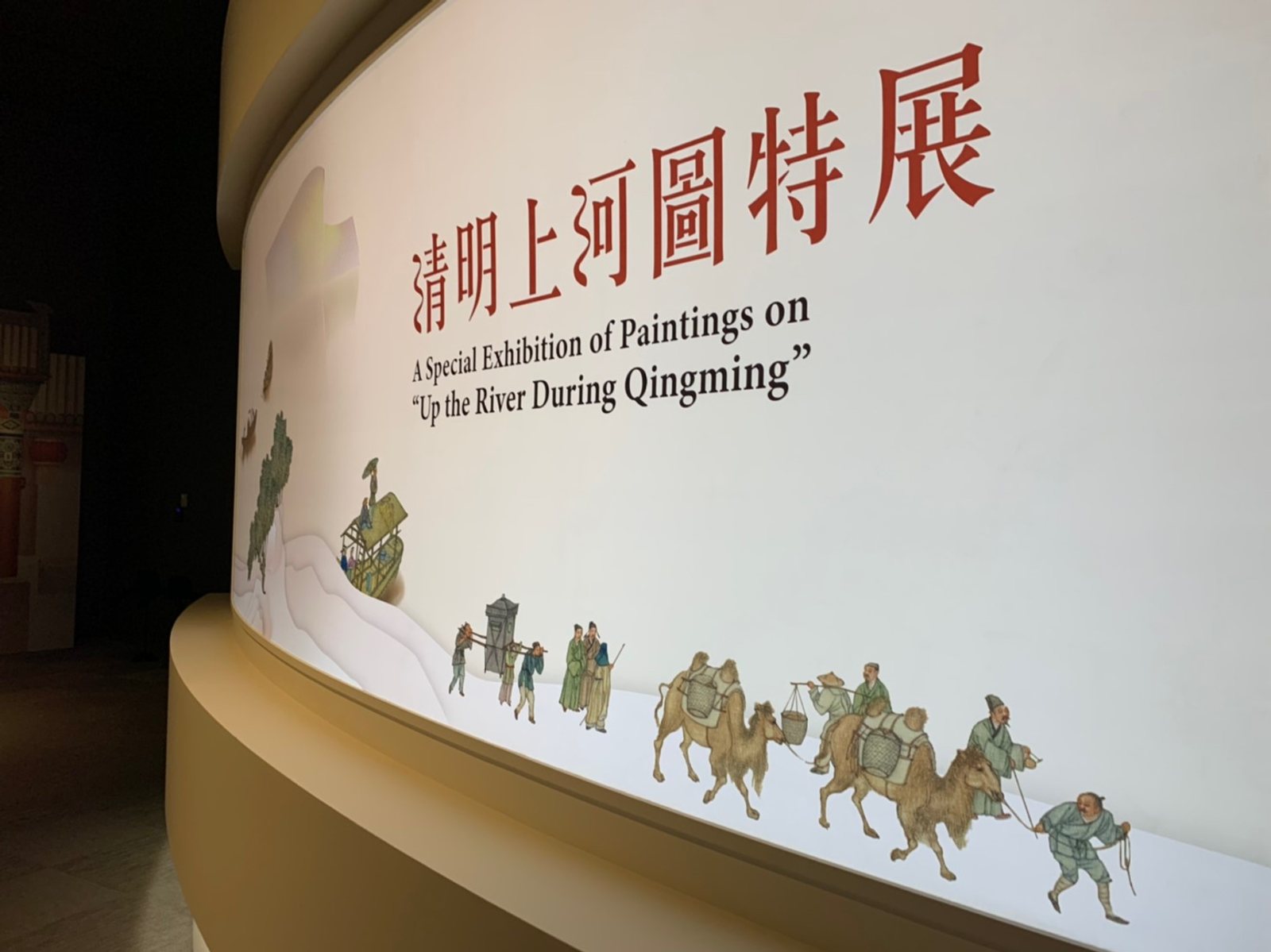 故宮南院弧形入口牆面，畫中人物與駱駝隊剪影沿牆展開成入場隊伍