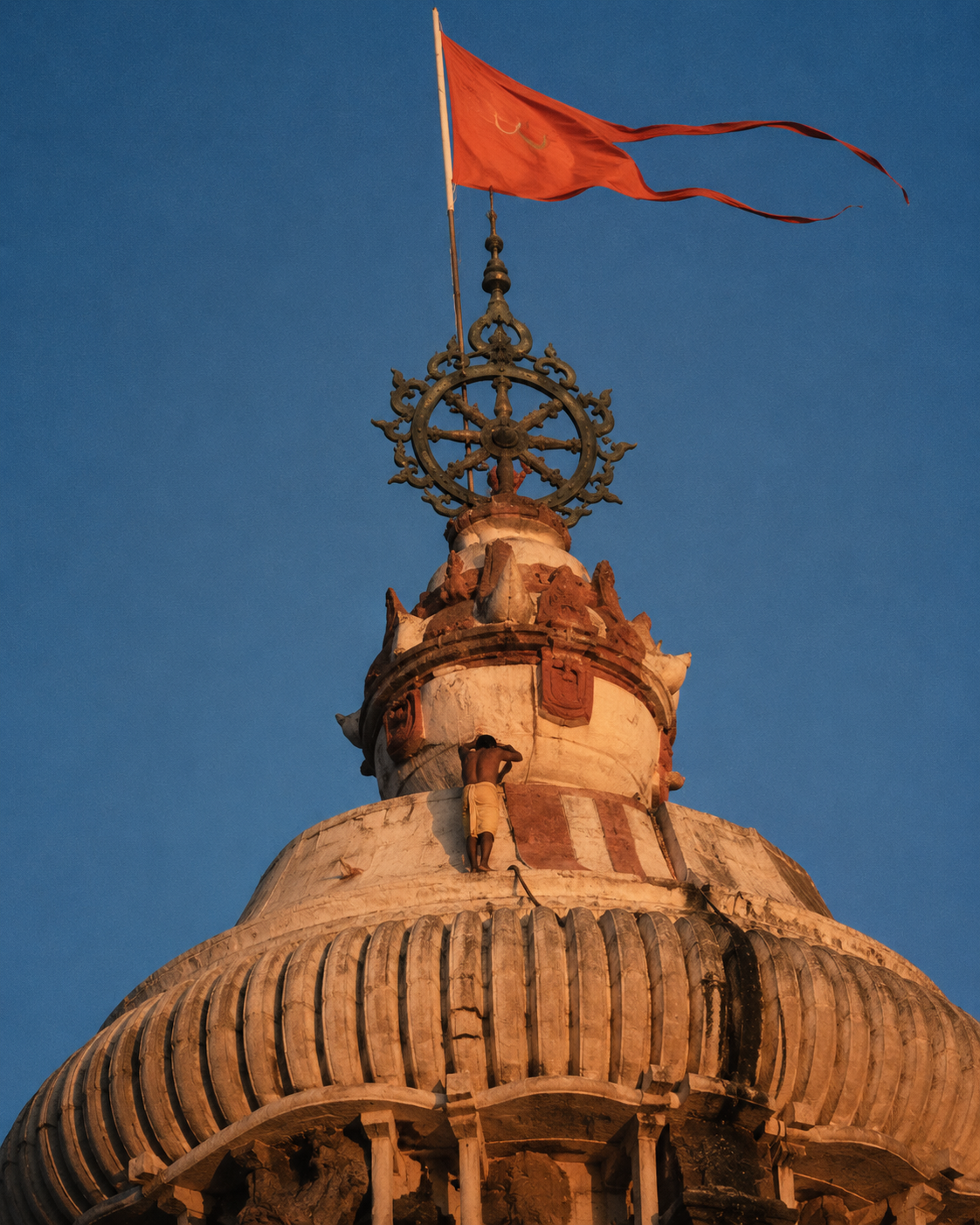 The cream-white Kalinga spire of the Jagannath Temple, with its flag and brass Nilachakra wheel