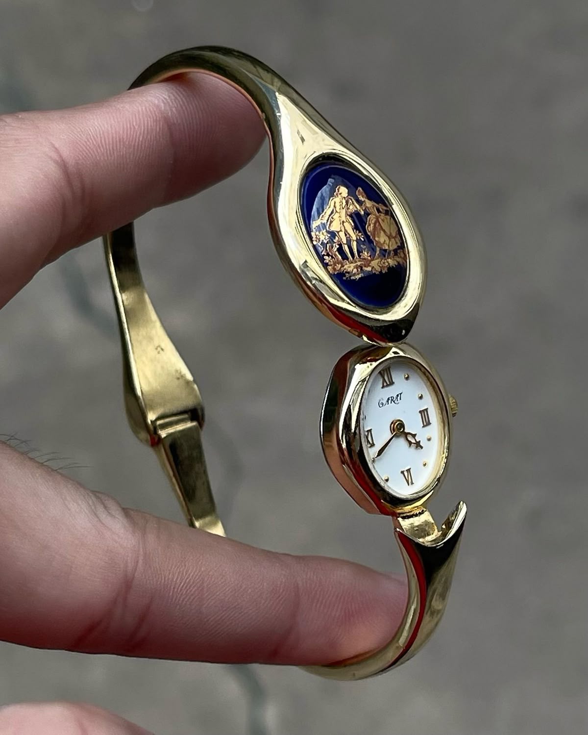 Gold-tone bangle watch with a miniature dial and blue decorative detail