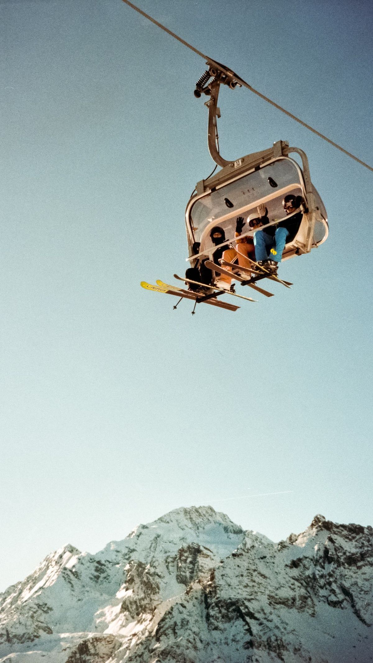 Skiers riding a chairlift above snow-covered mountains
