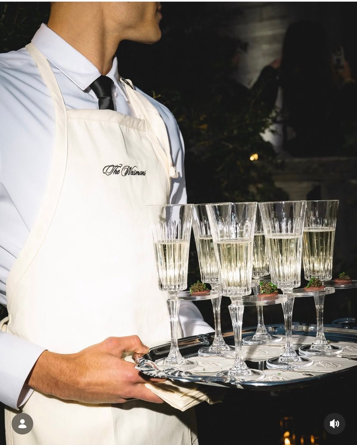 Server carrying a metal tray of filled glasses
