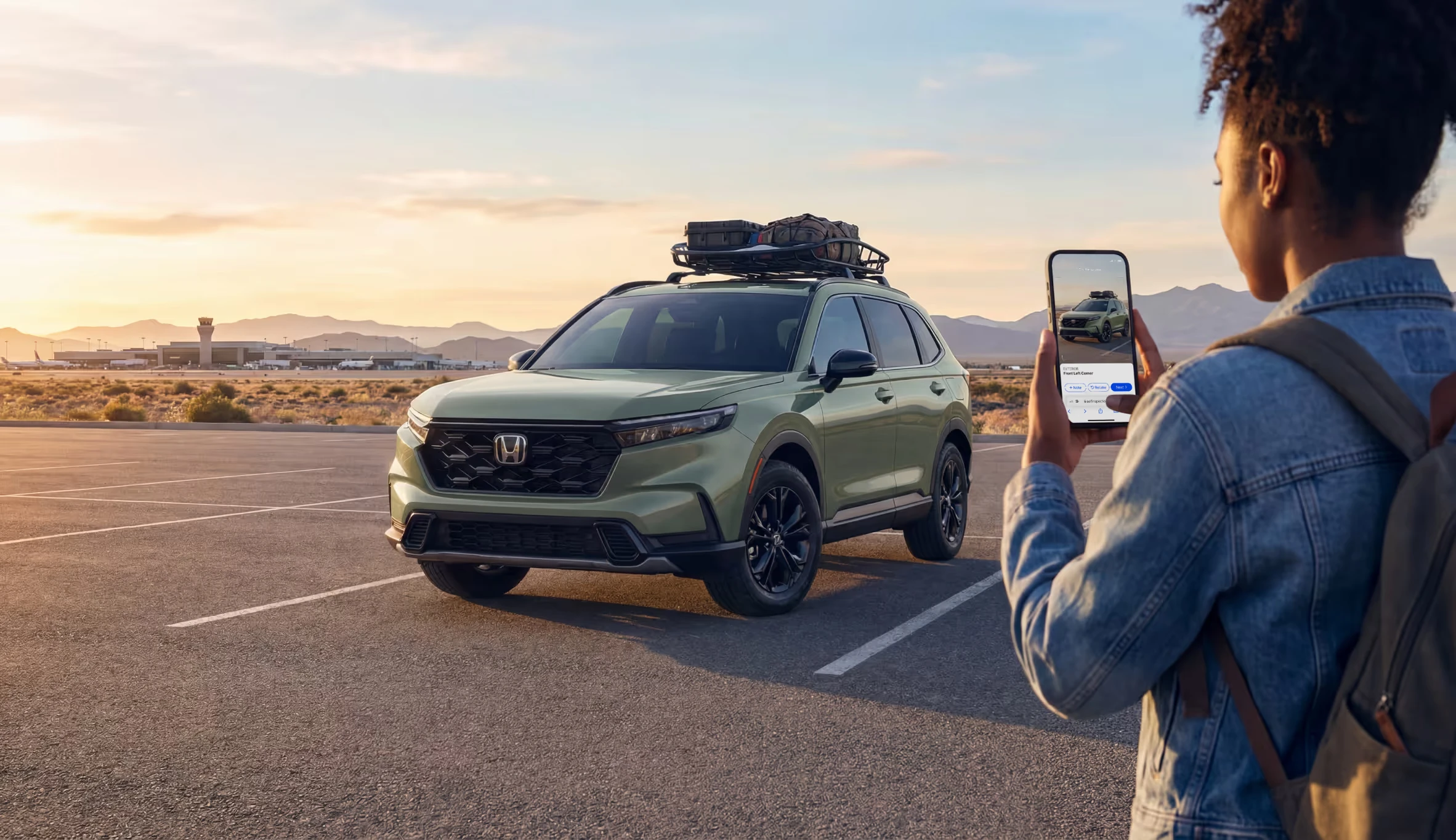A person photographing a green SUV with the Self Inspection app in a desert setting