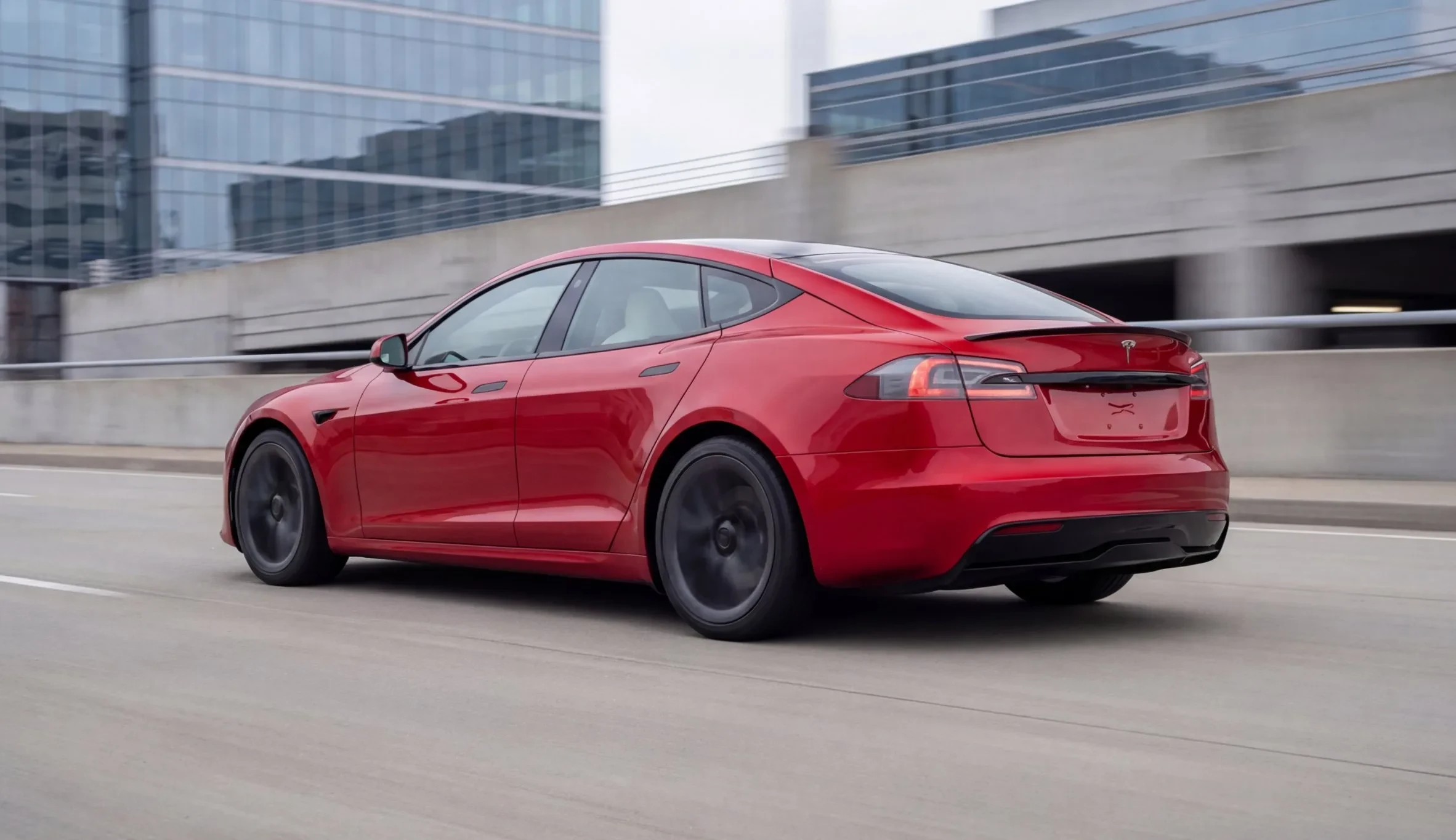 Red sedan driving on an elevated city road