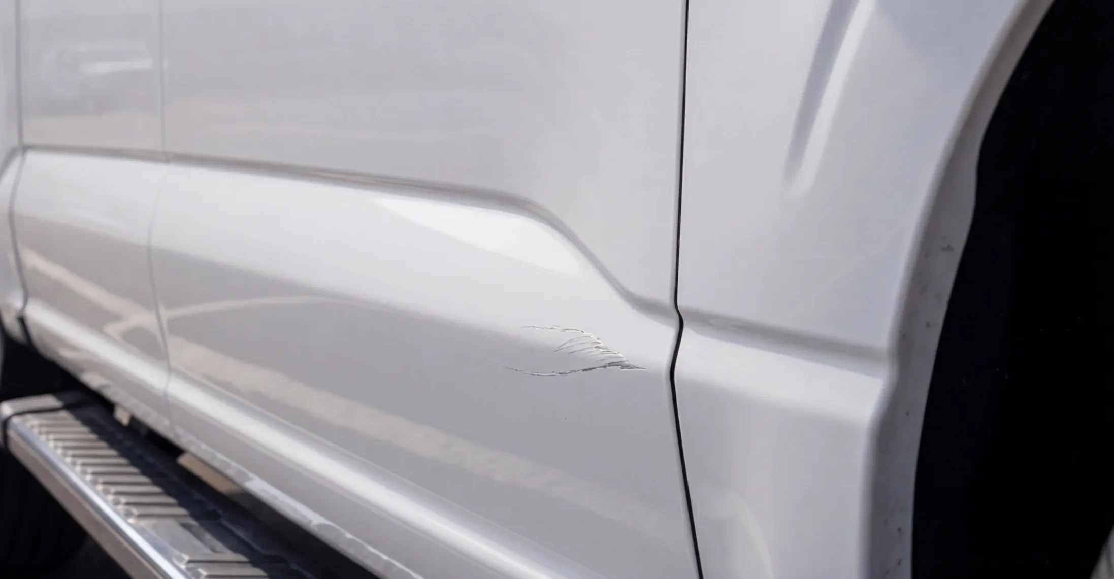 Heavy scratch on the front door of a white pickup