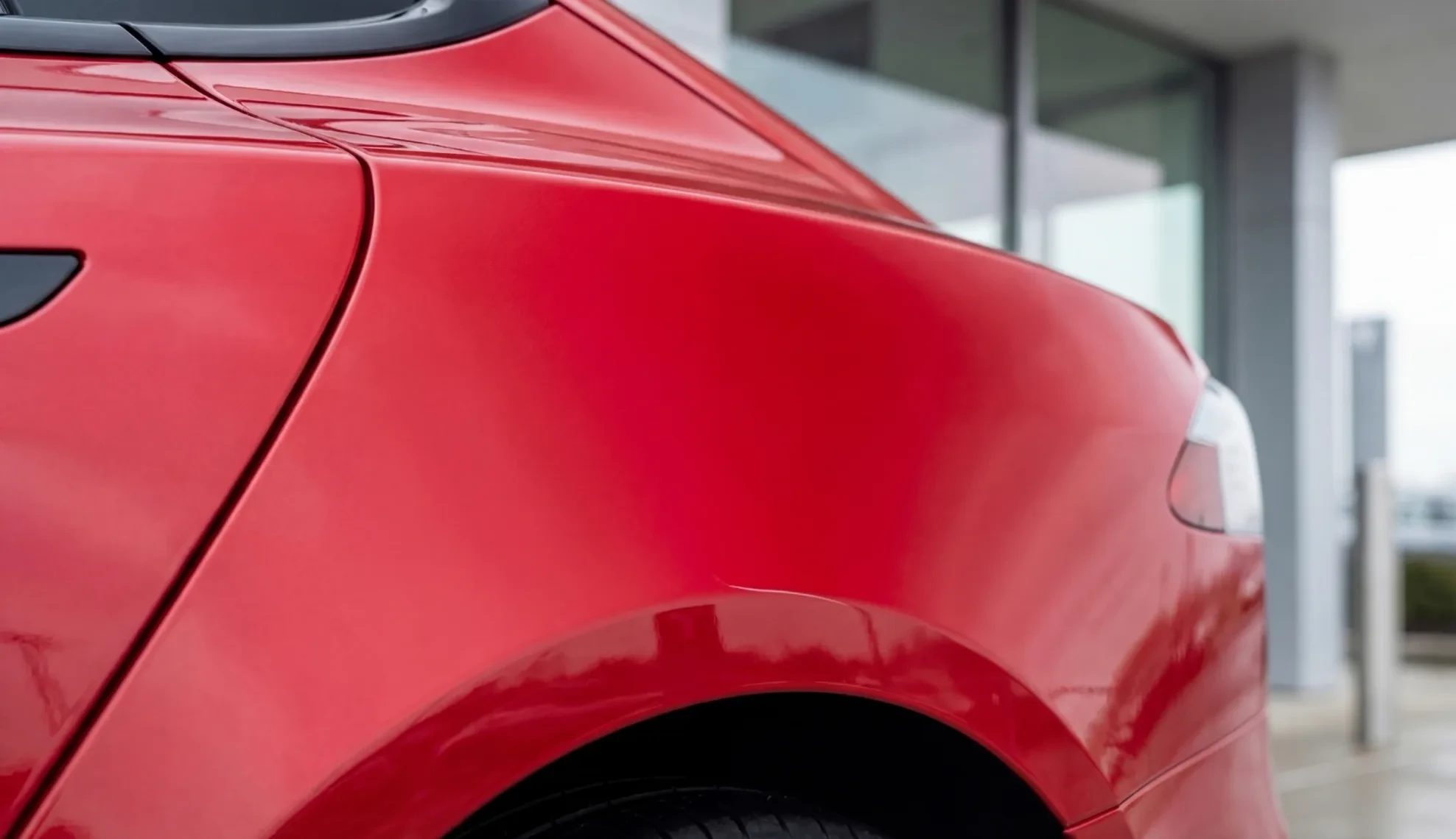 Scratch on the rear quarter panel of a red sedan