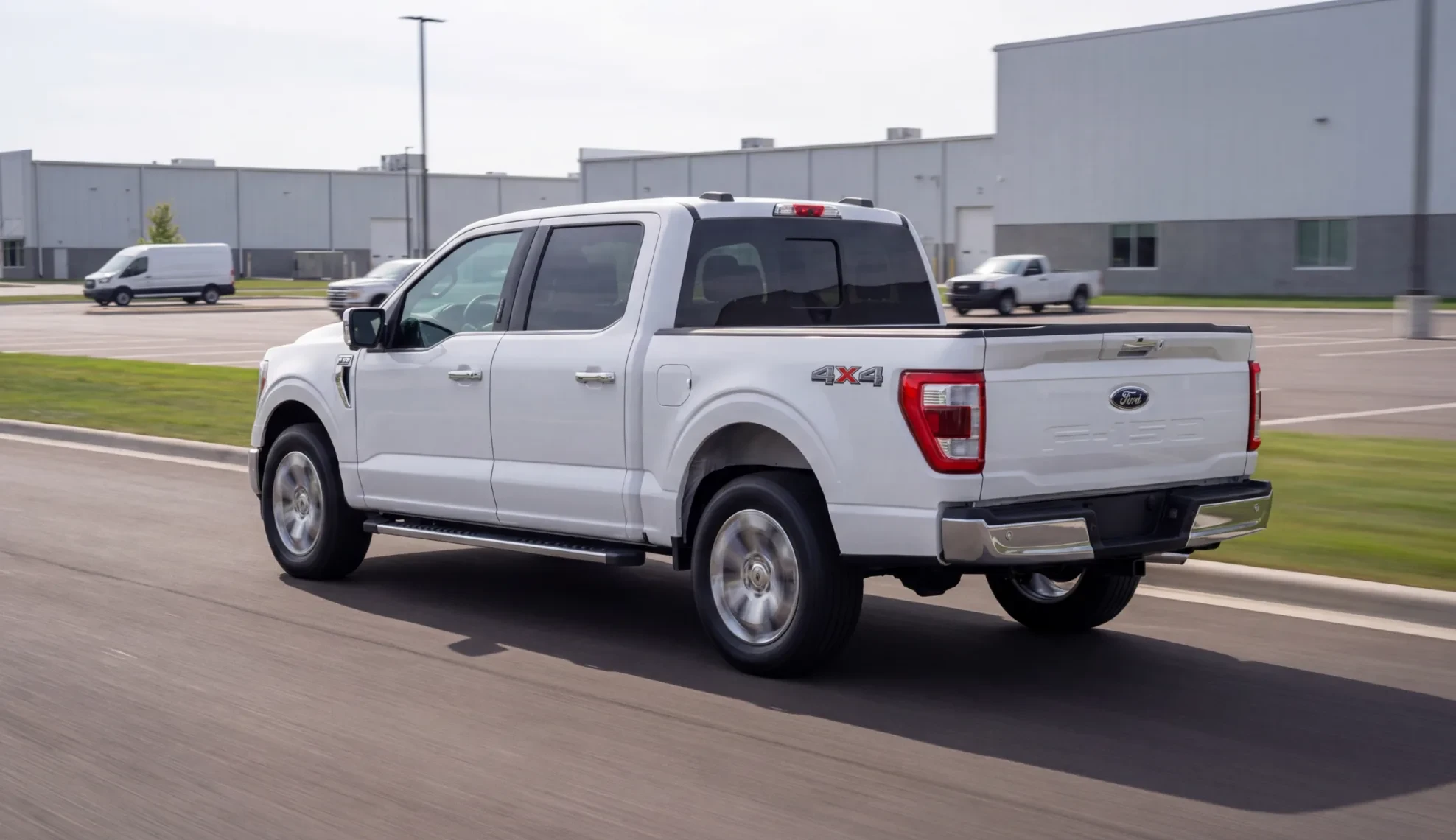 White pickup driving past a warehouse, with damage on the bedside