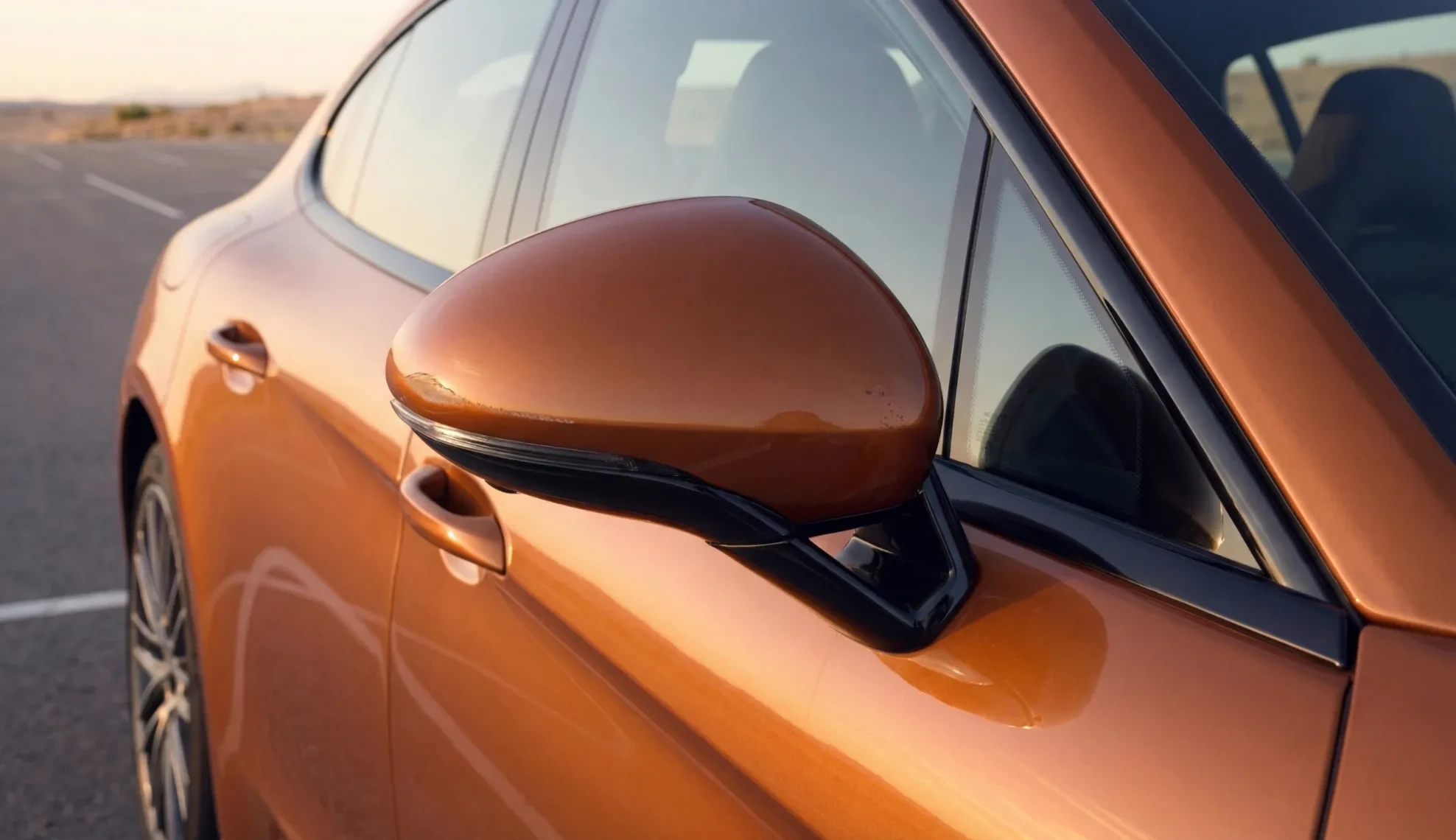 Paint chip on the side mirror of an orange sedan