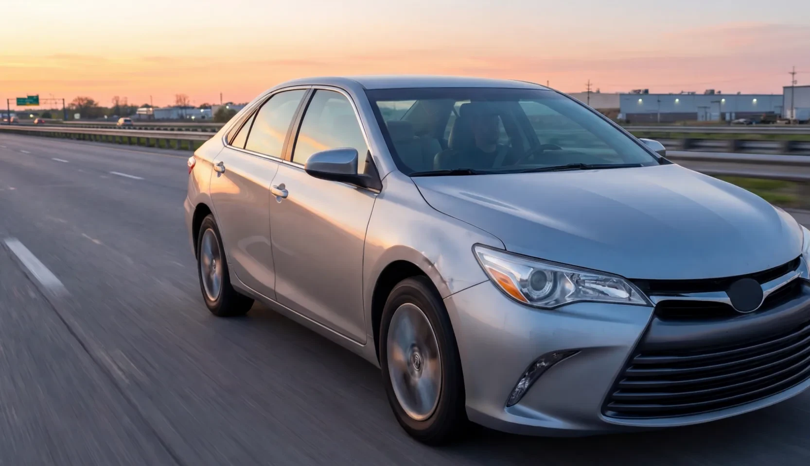 Silver sedan on a highway at sunset