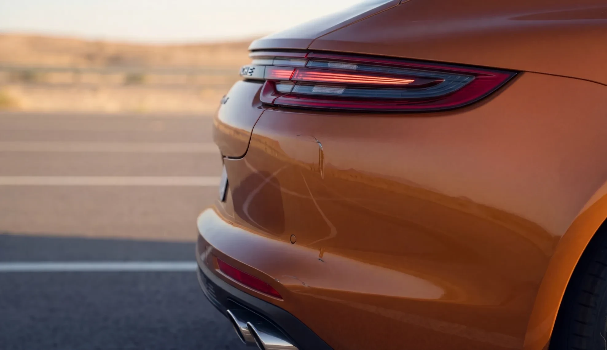 Scratch on the rear quarter panel of an orange sedan