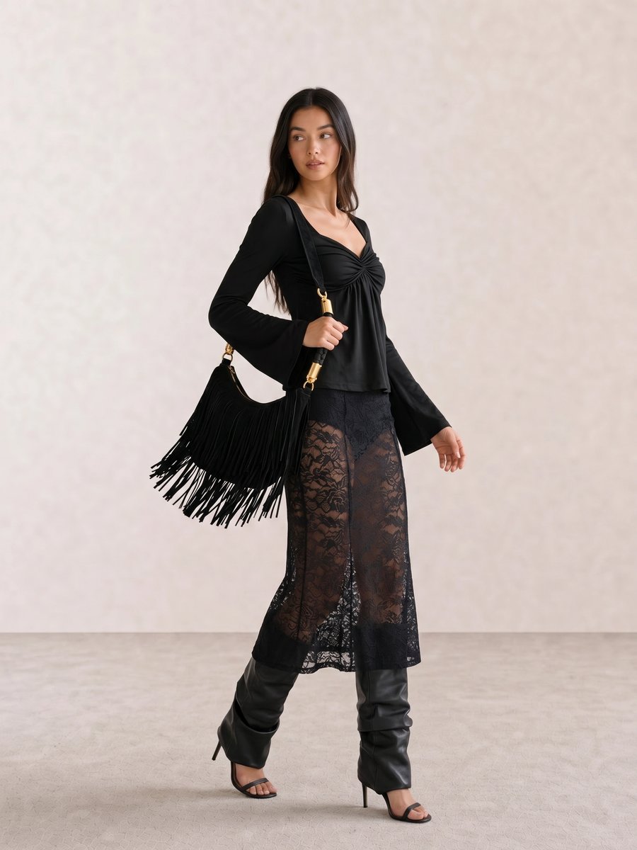 Black outfit with a flare-sleeve top, sheer lace midi skirt, suede fringe bag, and fold-over leather heels