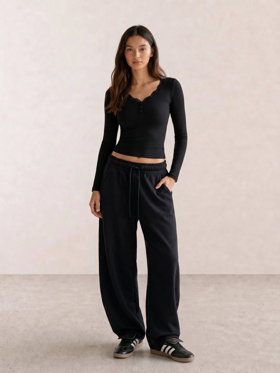 All-black casual outfit with a lace-trim henley top, barrel-leg sweatpants, and black Samba sneakers