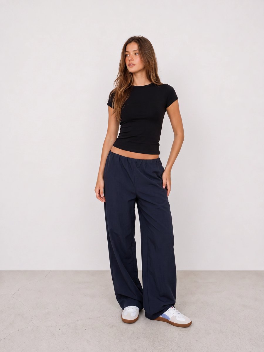Woman wearing a black tee, navy wide-leg pants, and white sneakers