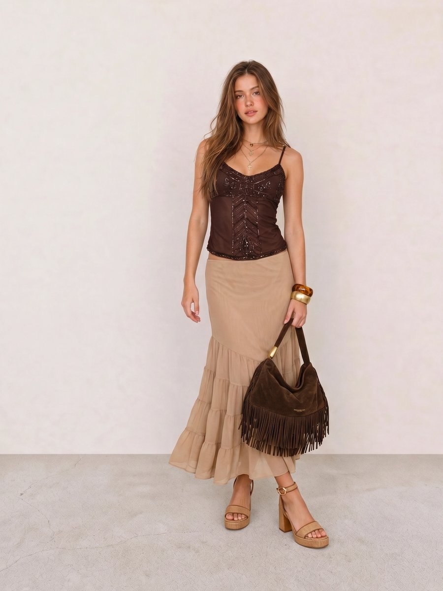 Boho outfit with a brown beaded corset top, sand tiered chiffon maxi skirt, fringe bag, and raffia heels
