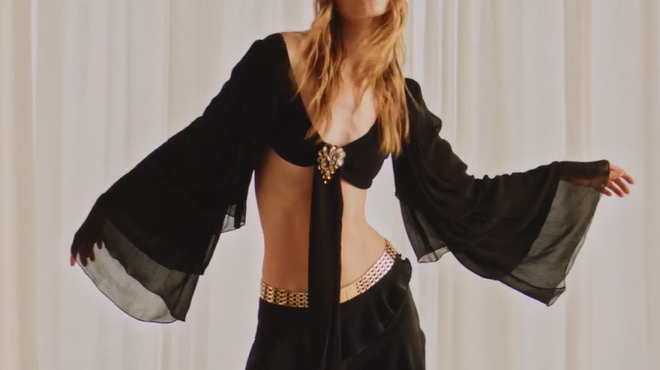 Black sheer bell-sleeve kimono layered over a white cow-print mini skirt