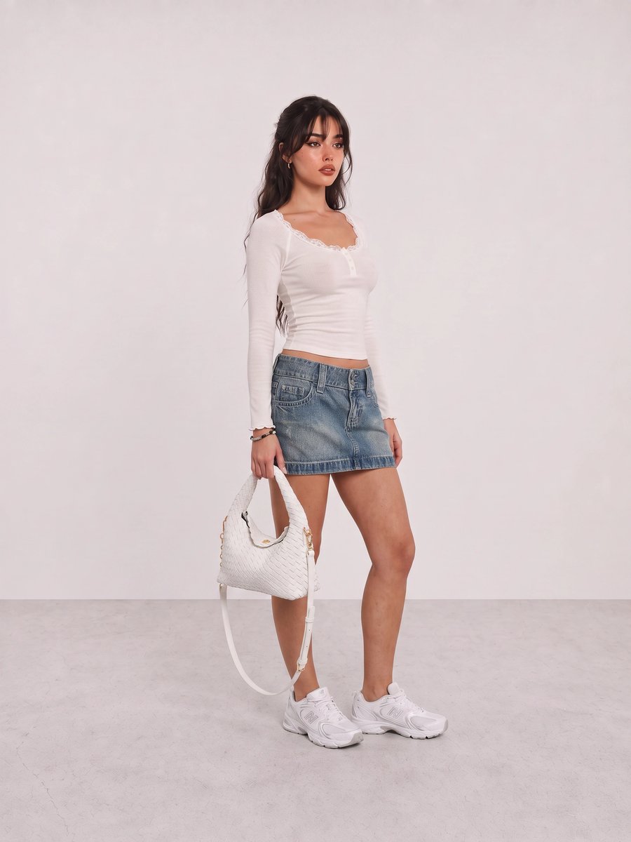 Woman wearing a white lace-trim top, a denim mini skirt, white sneakers, and a woven white shoulder bag