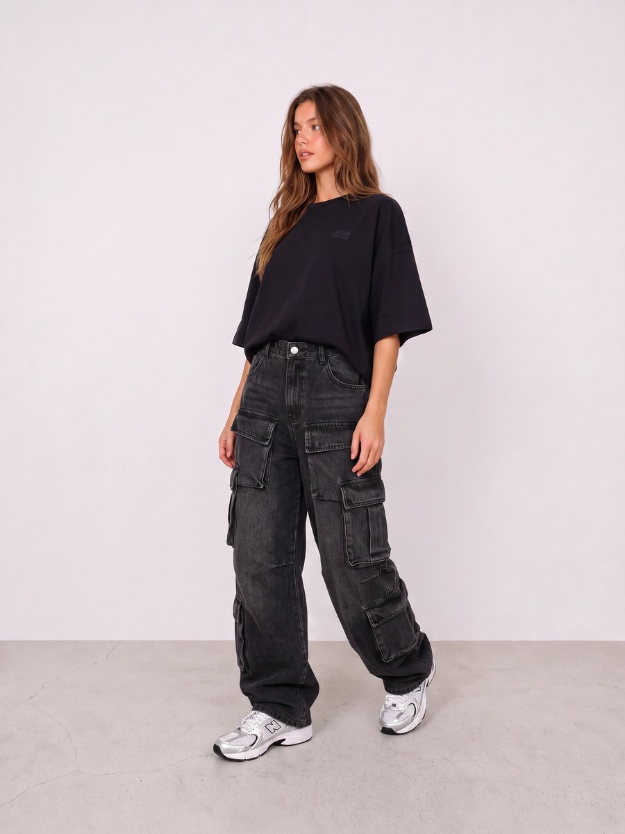 Woman wearing an oversized black tee, washed black cargo jeans, and silver sneakers