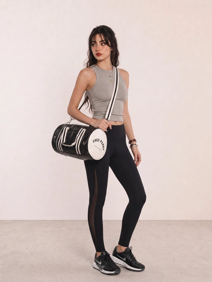 Woman wearing a grey crop tank, black leggings, black running shoes, and a black duffel bag