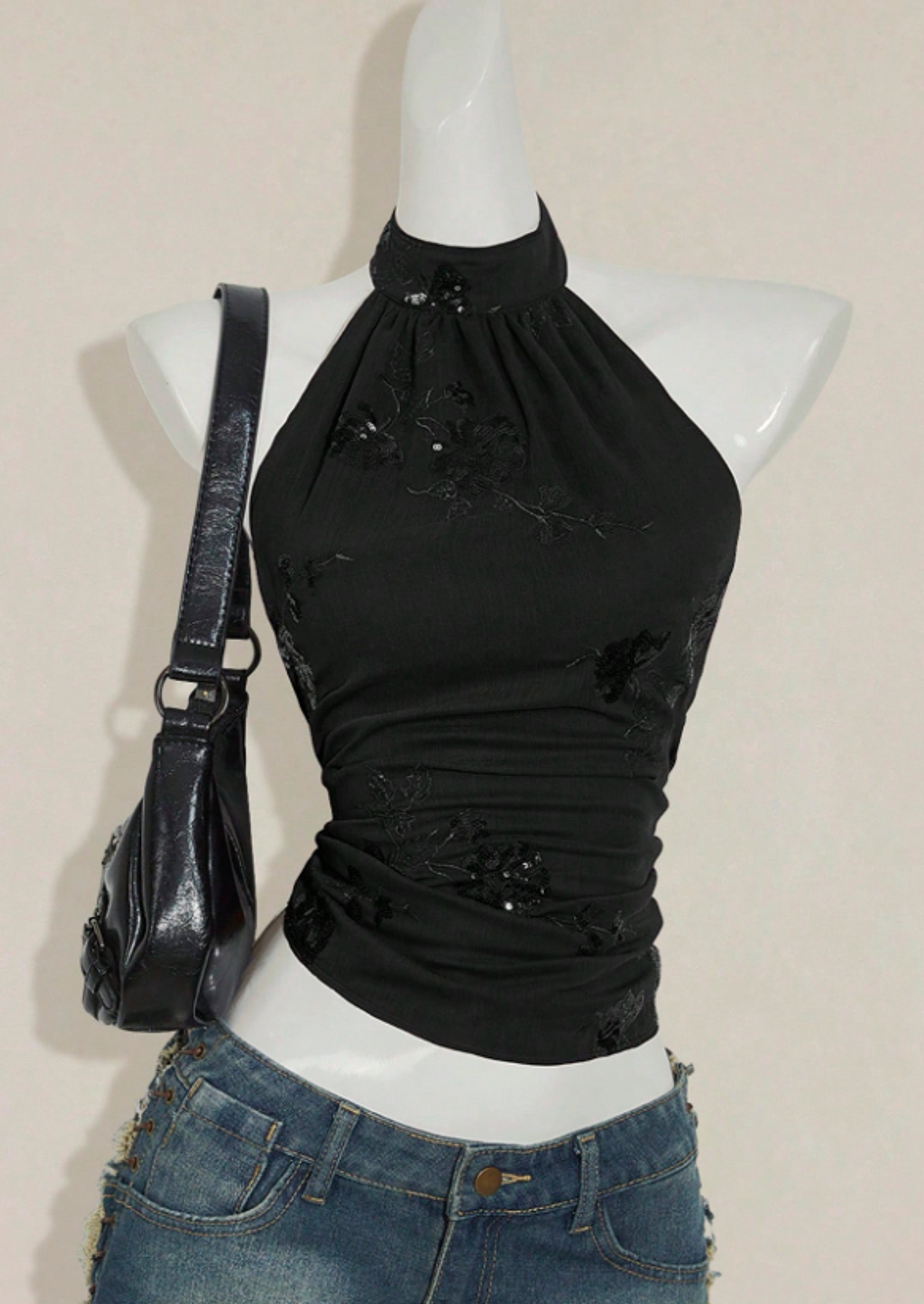 Black sequin halter top styled with black flare jeans and leather sneakers