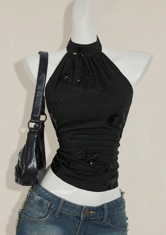 Black sequin halter top styled with black flare jeans and leather sneakers